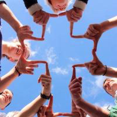 woman in brown jacket standing on green grass field near body of water during daytime